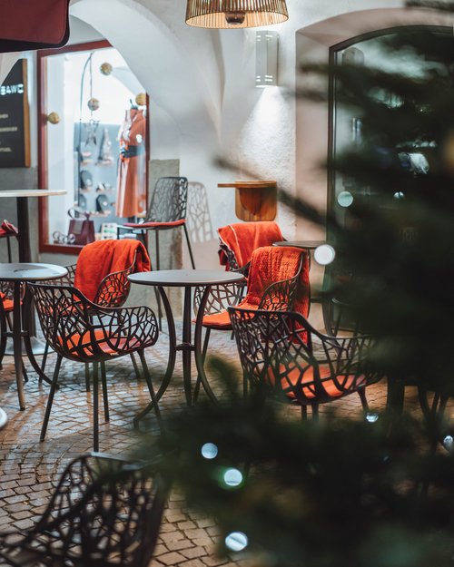 Leere Außenterrasse mit Möbeln und roten Decken unter Lampenbeleuchtung
