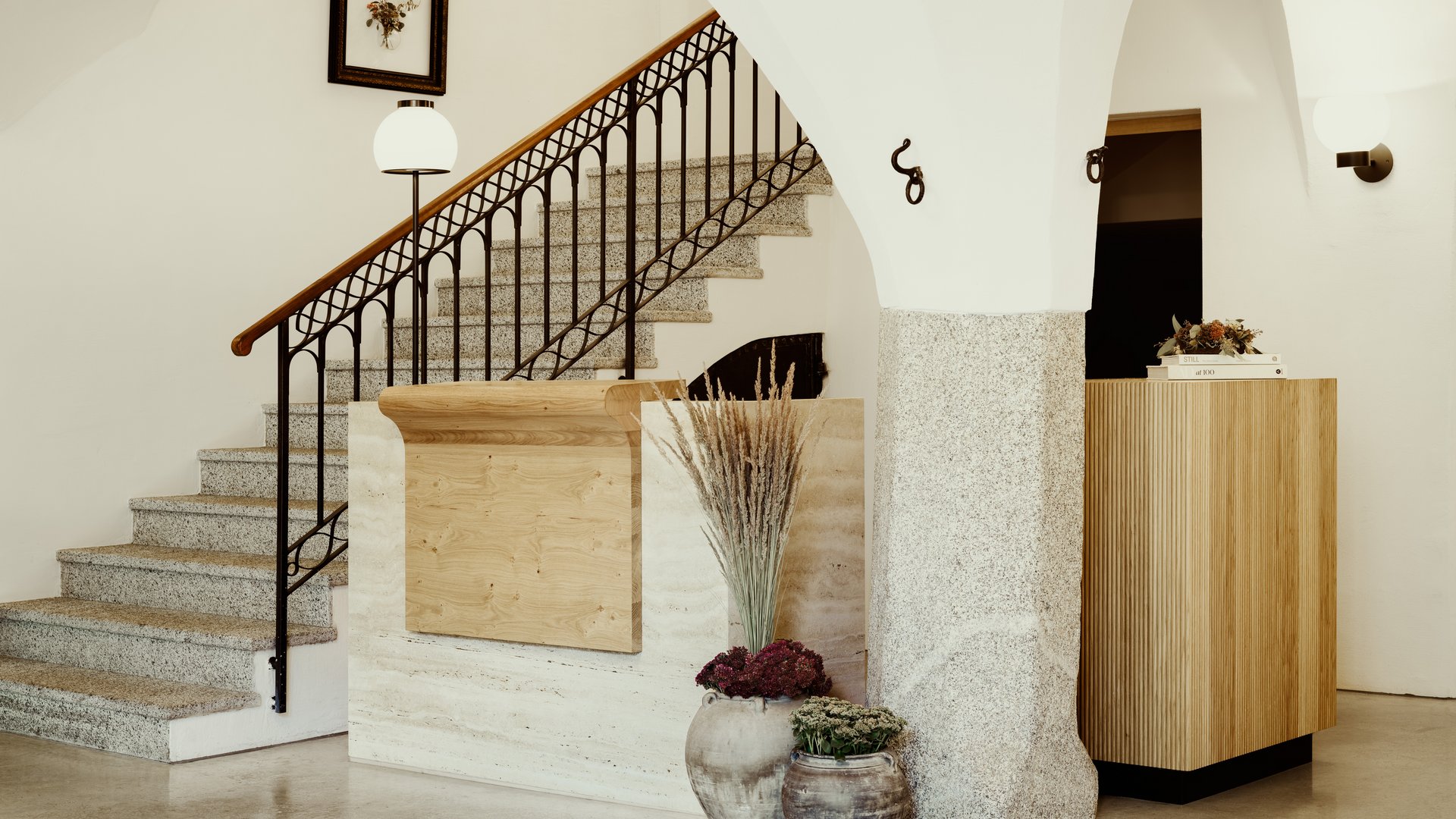 Moderne Rezeption mit Treppe, Blumenvasen und hellen Bögen