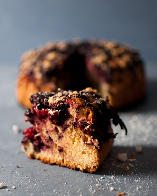 Stück Heidelbeerkuchen mit Streuseln auf grauem Untergrund