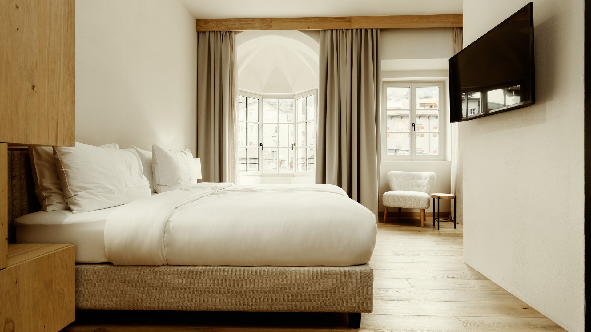 Modernes Hotelzimmer mit großem Bett, Stuhl und Wandfernseher