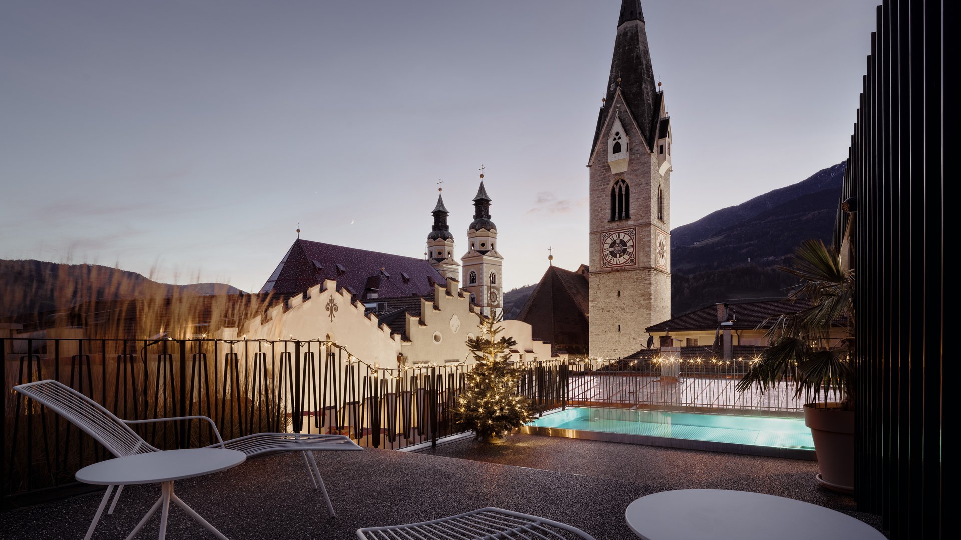 Abendlicher Blick auf Terrasse mit Pool und Kirchturm im Hintergrund