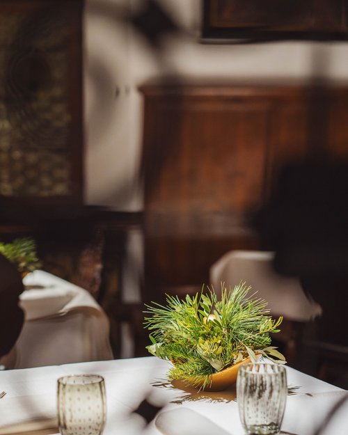 Tisch mit Tischdecke, Glas, Besteck und grünem Blumenschmuck