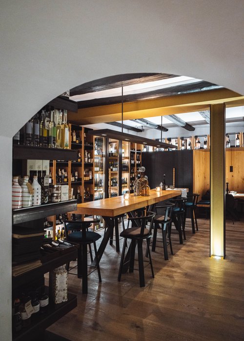 Gemütlicher Barbereich mit Holztheke, Stühlen und Regalen voller Flaschen