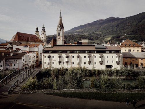 Stadtansicht mit Kirche, Fluss und Bergen im Hintergrund