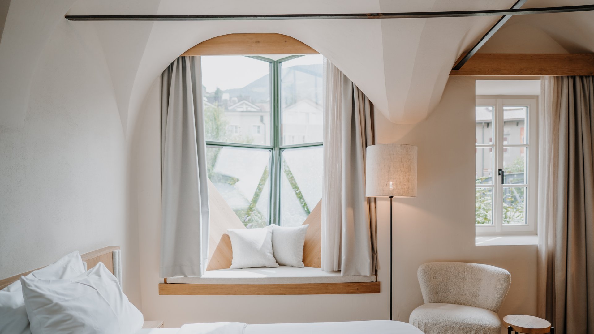 Helles Schlafzimmer mit gepolstertem Fensterplatz und gemütlichem Sessel