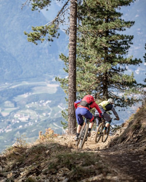 Two mountain bikers riding on a mountain trail overlooking the valley