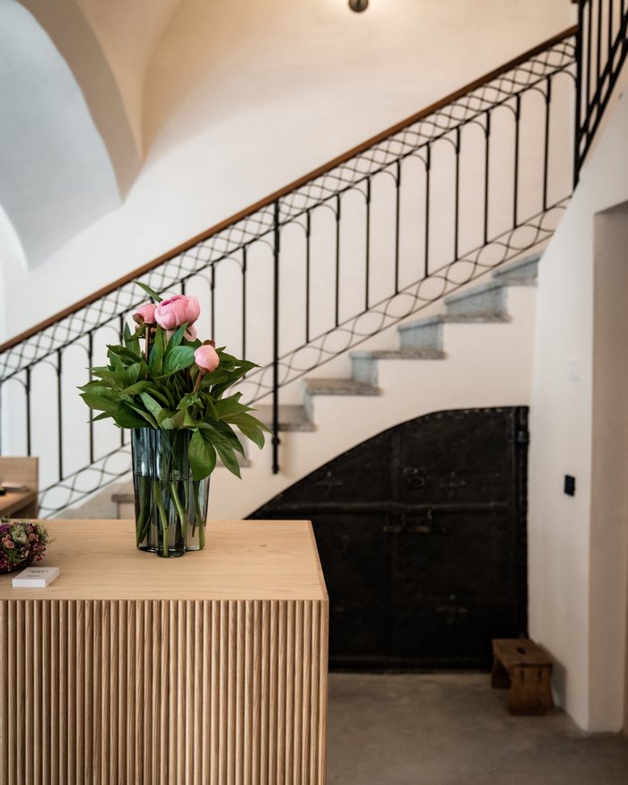 Blumen in Vase auf Holztisch vor Treppe und Tür im Innenraum