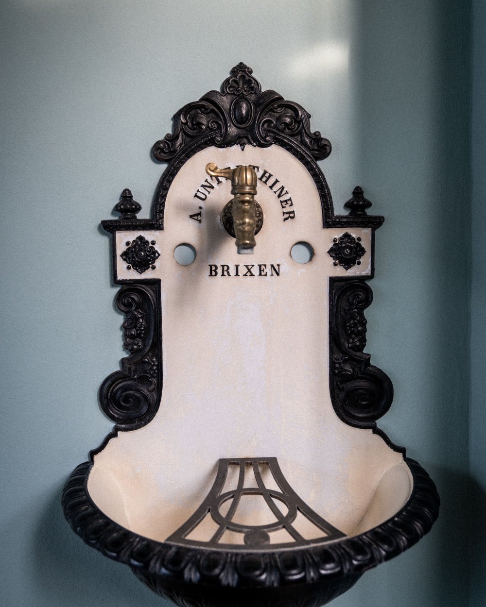 Antique wall-mounted sink with black decoration and golden faucet