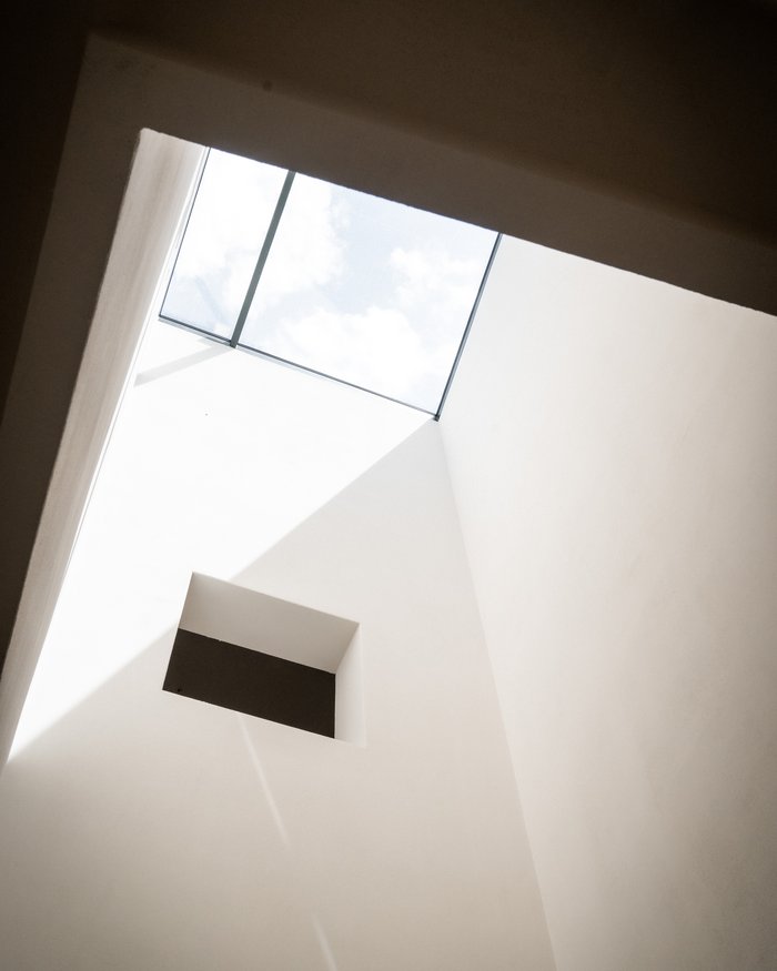 Blick nach oben auf ein quadratisches Oberlicht und weiße Wände eines Innenraums
