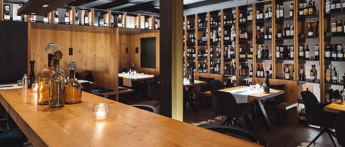 Gemütlicher Weinbereich eines Restaurants mit Holzregalen und Tischen