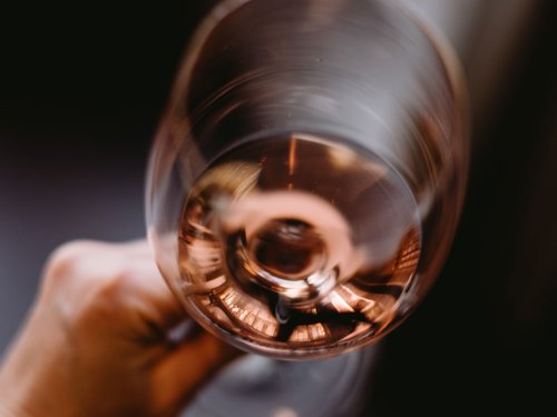 Hand hält Glas mit roséfarbenem Wein