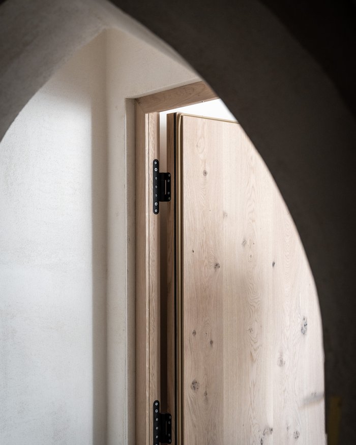 Holztür leicht geöffnet mit gewölbtem Türrahmen aus Stein