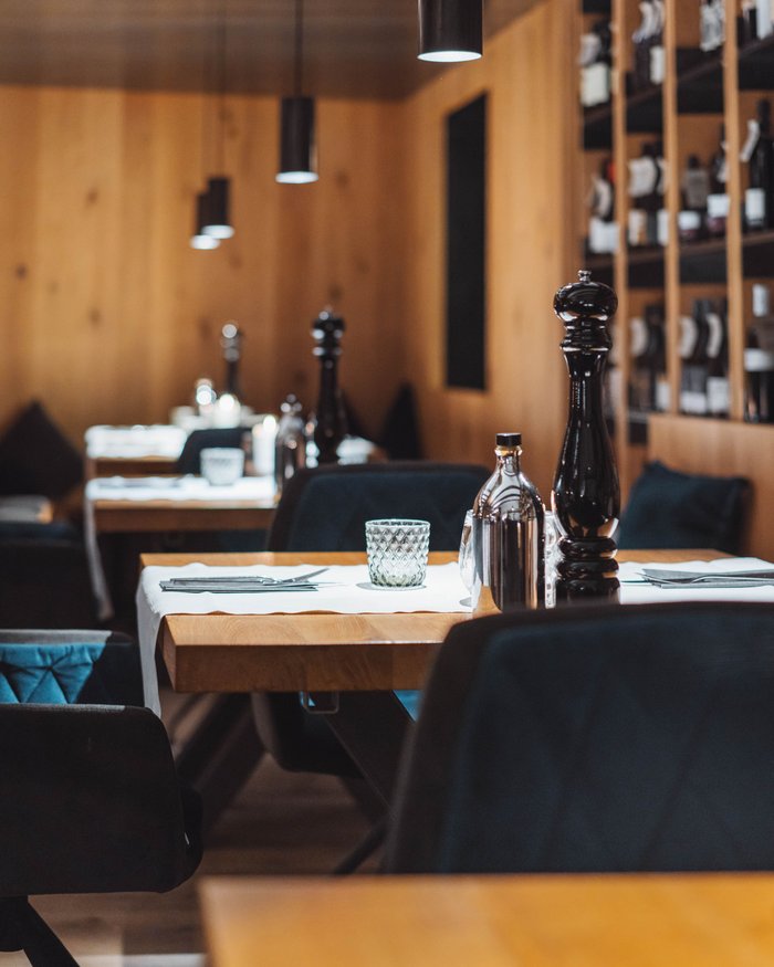 Restaurant mit Holztischen und dunklen Stühlen, Tischgedeck mit Pfefferstreuer