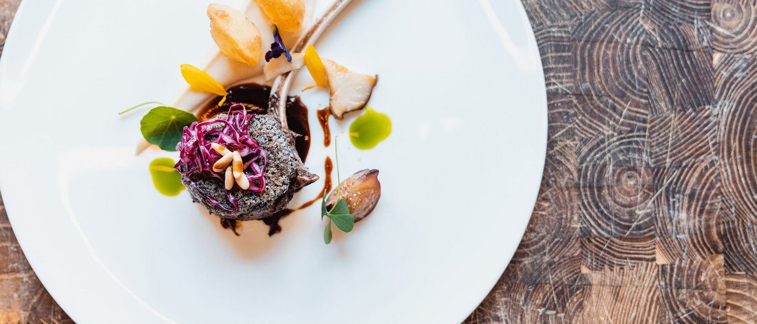 Elegantly plated gourmet lamb chop with colorful garnishes on a white plate