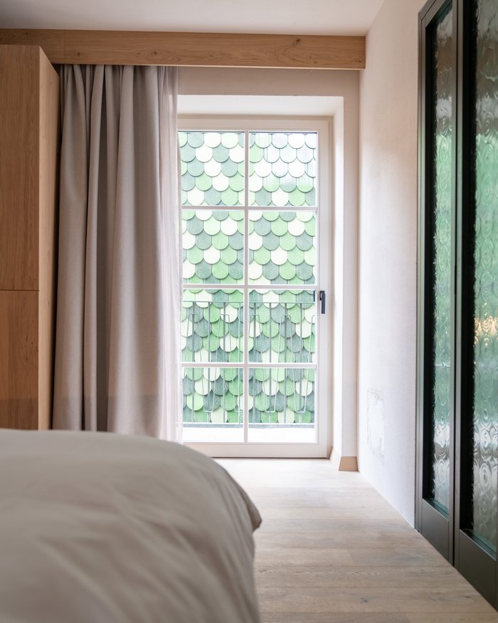 Schlafzimmer mit Fenster und grüner Schindelwand draußen