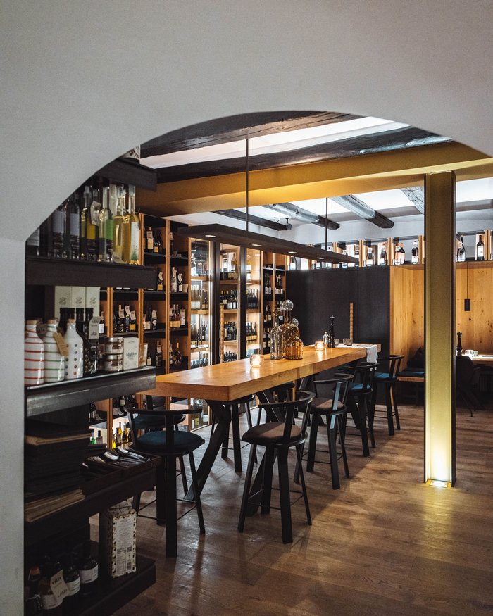 Gemütlicher Barbereich mit Holztheke, Stühlen und Regalen voller Flaschen