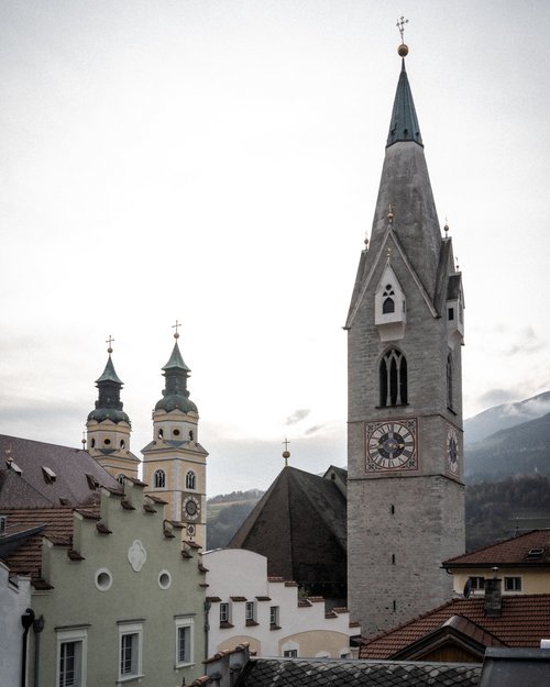 Clock tower and surrounding buildings in a mountain town under a cloudy sky